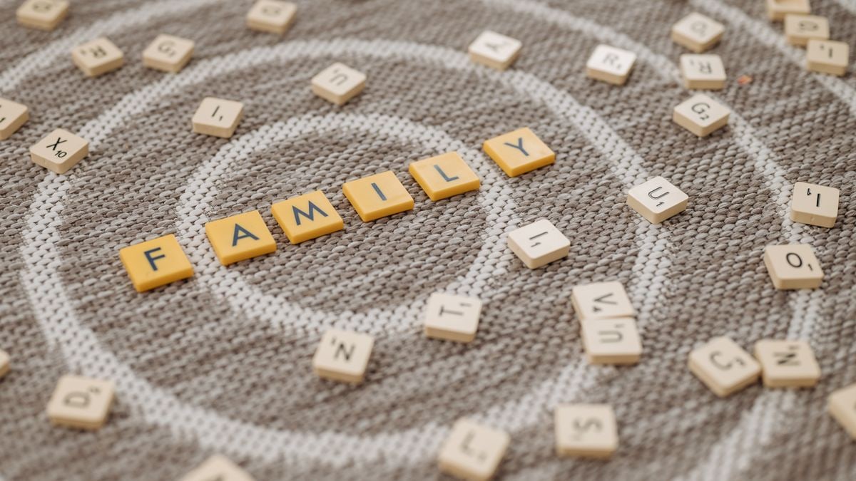 An artistic display of Scrabble tiles spelling 'FAMILY' on a textured carpet surface.
